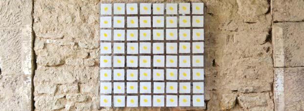 Nahaufname des Kunstwerkes „Saatgut” an der Wand der Wintringer Kapelle: 64 weiße, mit einem gelben Stempel versehene, quadratische Karten