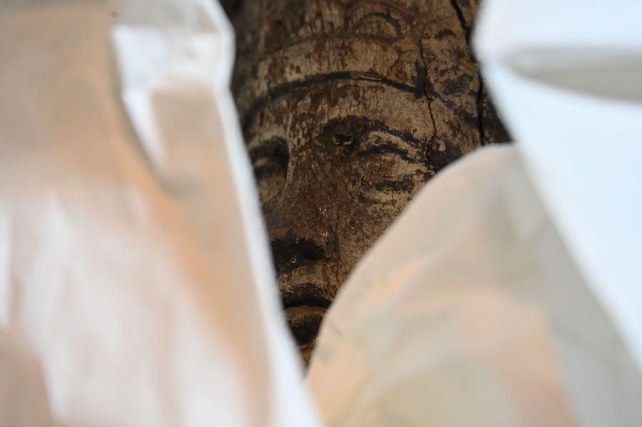 Gesicht einer Holzfigur lugt aus weißen Tüchern
