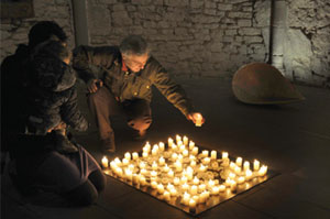 Mensch in der Dunkelheit der Wintringer Kapelle entzünden am Boden sitzend Kerzen