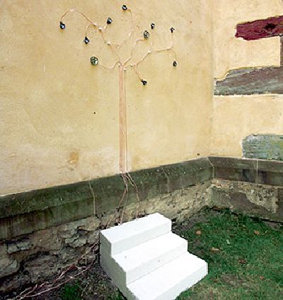 Treppenstufen vor Kappellaußenwand auf der ein stillisierter Baum angebracht ist